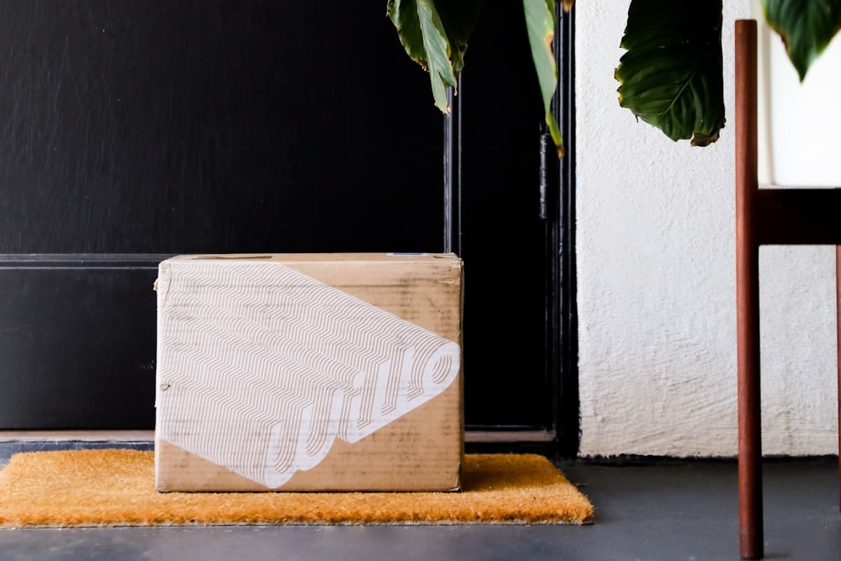 A cardboard delivery box left on a doormat at a front door